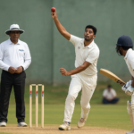 Ranji Trophy cricket match in Coimbatore with players in white uniforms on a sunny day