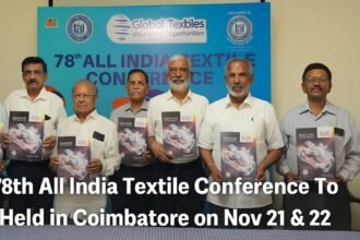Group of textile industry leaders unveiling the brochure for the 78th All India Textile Conference in Coimbatore, standing in front of a blue event backdrop.