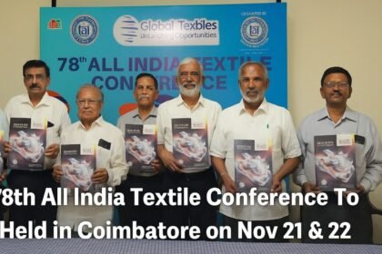 Group of textile industry leaders unveiling the brochure for the 78th All India Textile Conference in Coimbatore, standing in front of a blue event backdrop.