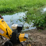 Man operating yellow shredder machine to convert water hyacinth into mulch at Sulur Big Tank Coimbatore